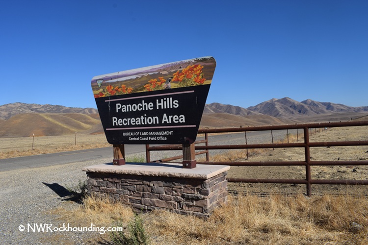 Panoche Hills Rockhounding in California near Mercey Hot Springs: The picture "Panoche Hills Rockhounding in California near Mercey Hot Springs recreation area sign" displays the entrance sign for Panoche Hills Recreation Area, set against a dry, grassy landscape with rolling hills and a distant mountain range.